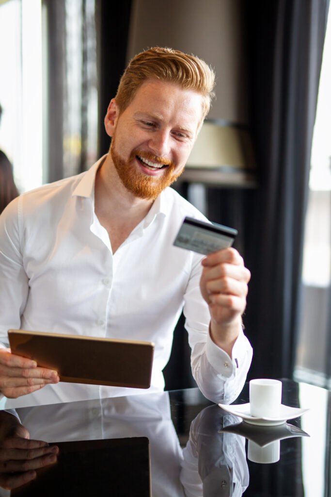 successful handsome business man holding credit card, using digital tablet. online shopping concept